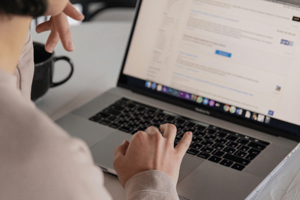A close-up of hands working on a laptop computer.