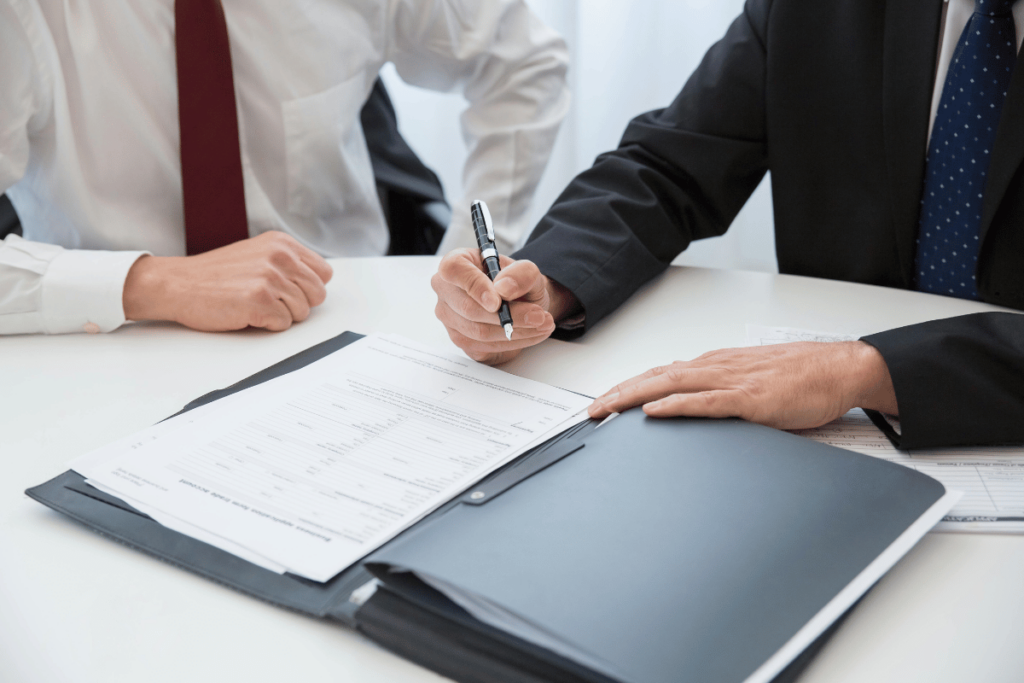 Business professionals signing documents during a meeting.