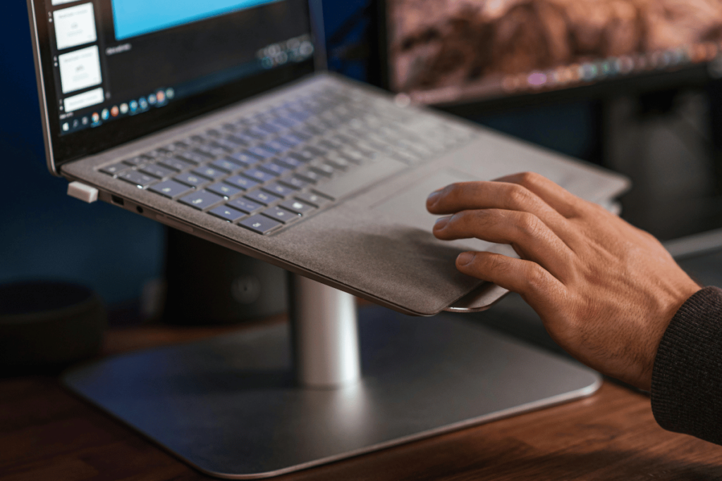 Close-up of a hand adjusting a laptop on a stand in a modern workspace.