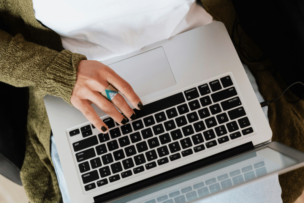 Overhead view of person typing on laptop keyboard with a green sleeve.