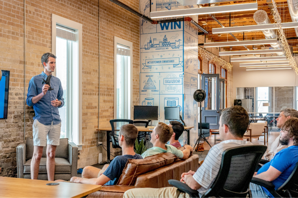 Speaker giving a presentation to an audience in a modern, open-concept office space.