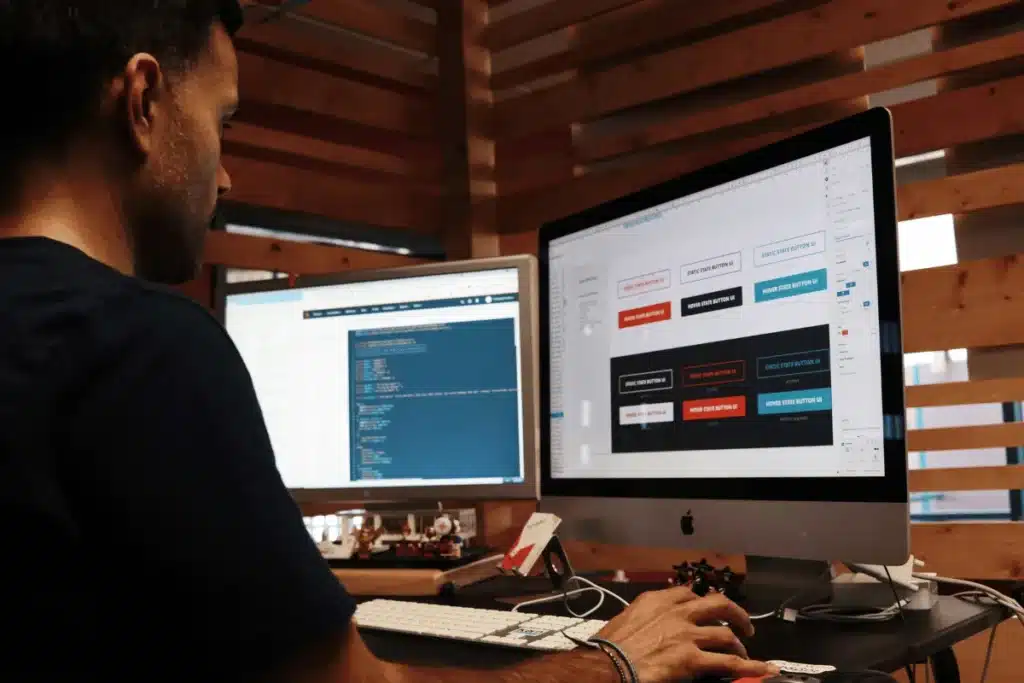 A developer working on UI design and coding on dual monitors in a modern workspace.