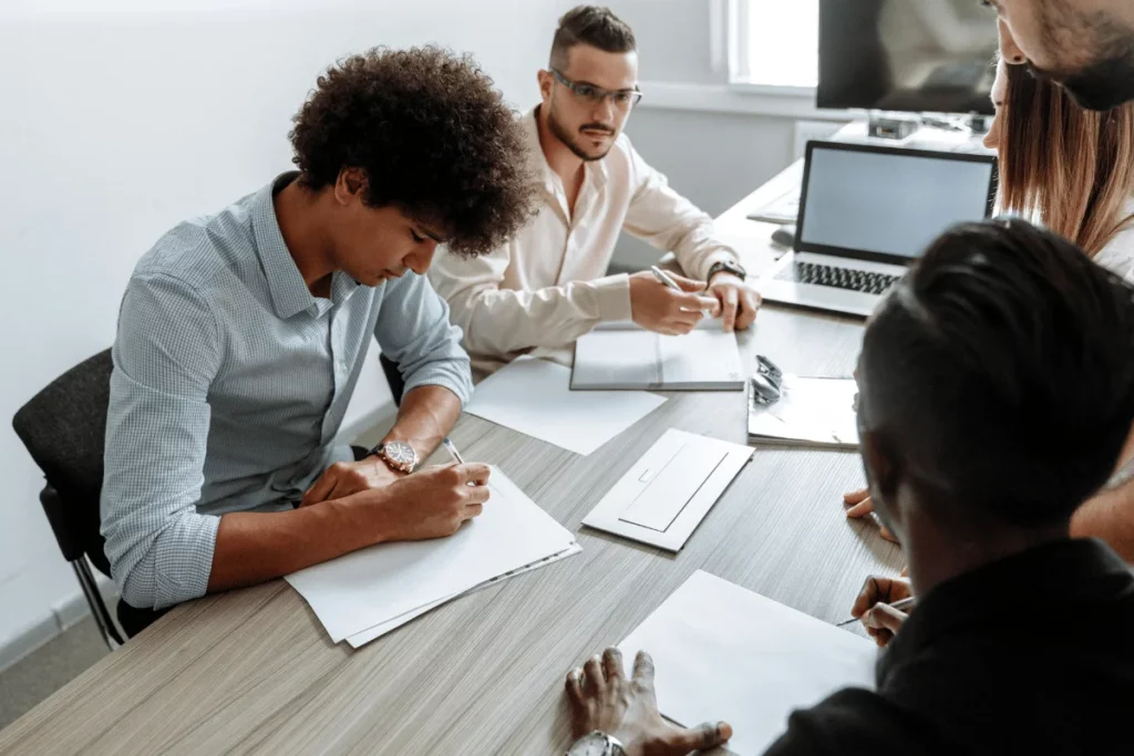 Team of professionals in a business meeting taking notes around a conference table.