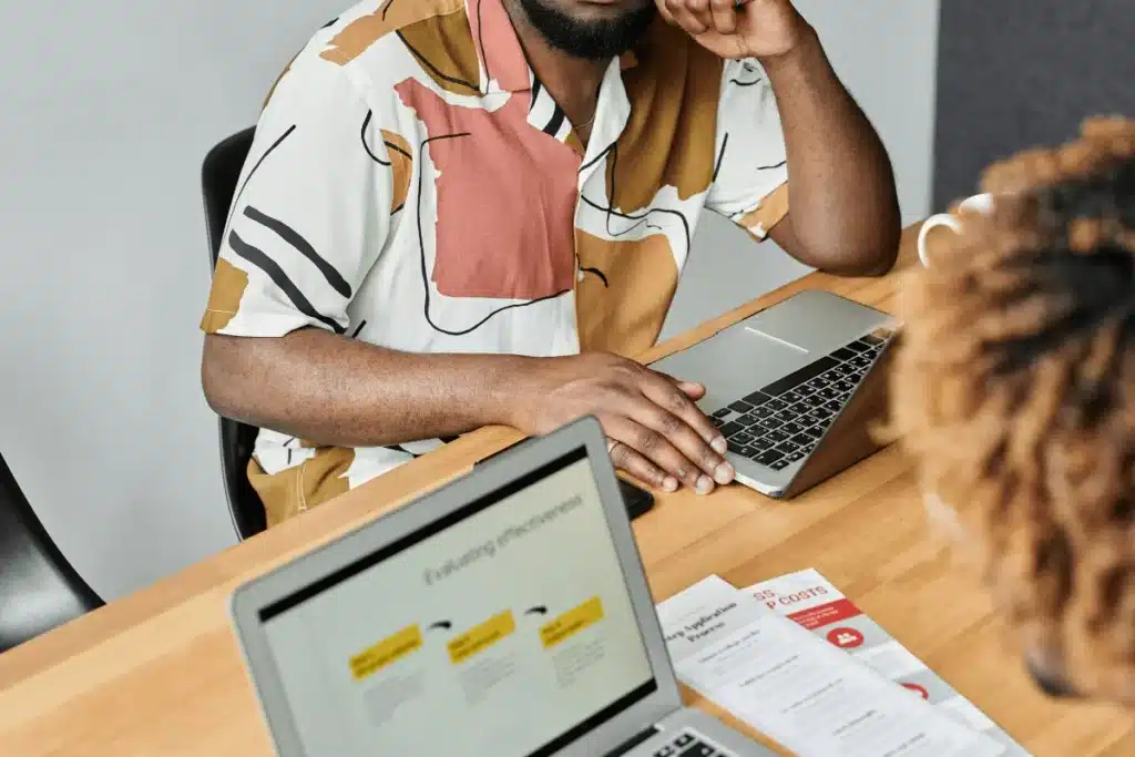 Team member in a creative shirt using a laptop during a meeting.