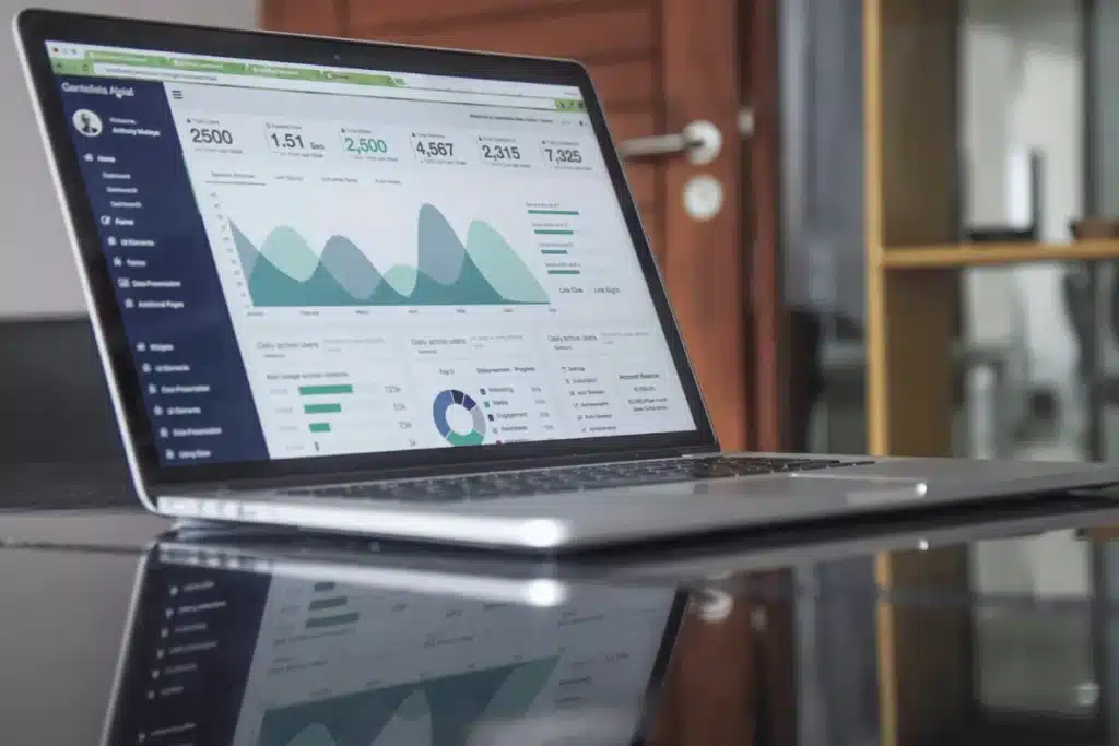 A laptop displaying a detailed data analytics dashboard with graphs and metrics on a sleek black table.