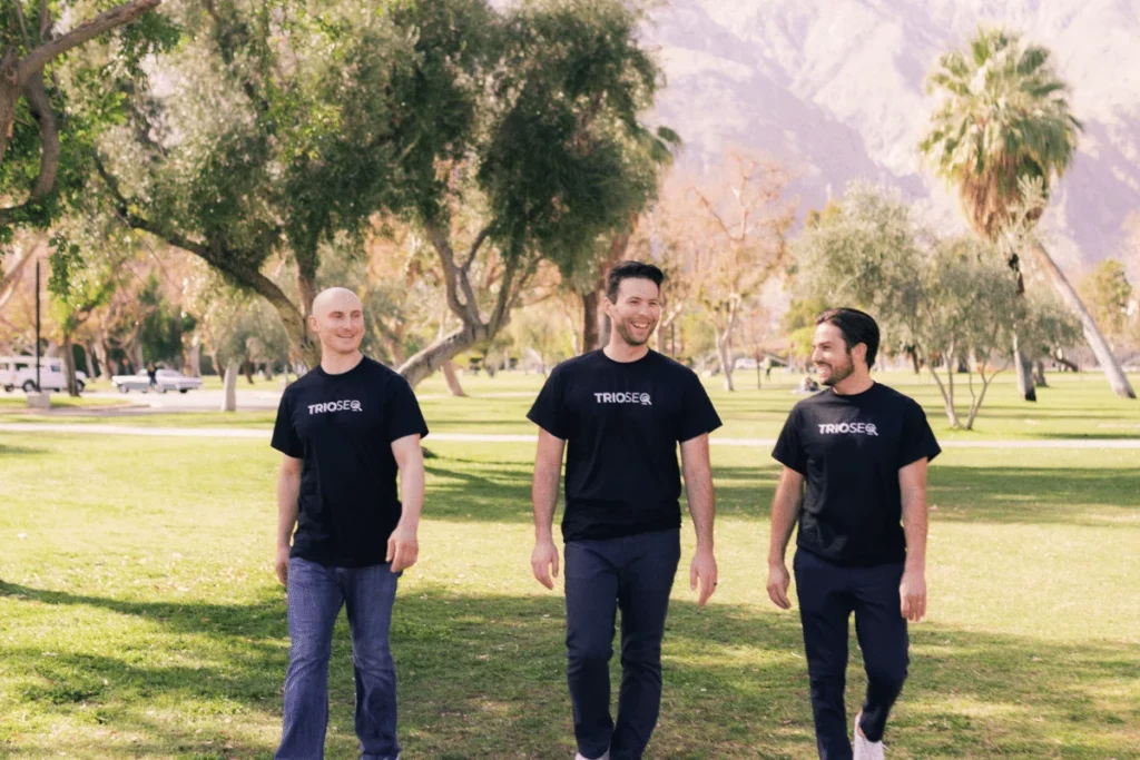 Smiling trio Nathan, Steven, and Connor model black TRIOS® t-shirts outside.