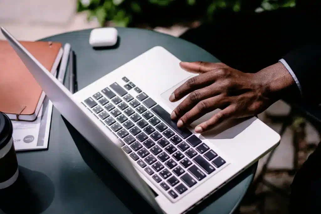 Close-up of a business person's hands using a laptop, accessories arranged on a round table.