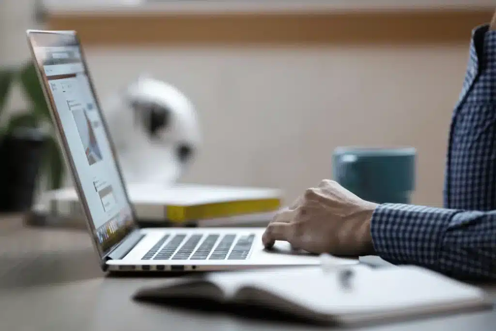 Hands typing on a laptop in a cozy home office setting.