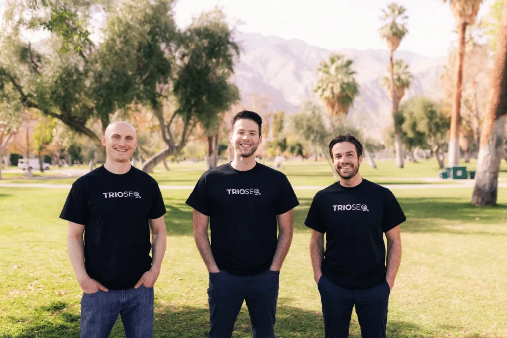 Trio of colleagues, Nathan, Steven, Connor, pose in branded apparel outdoors.