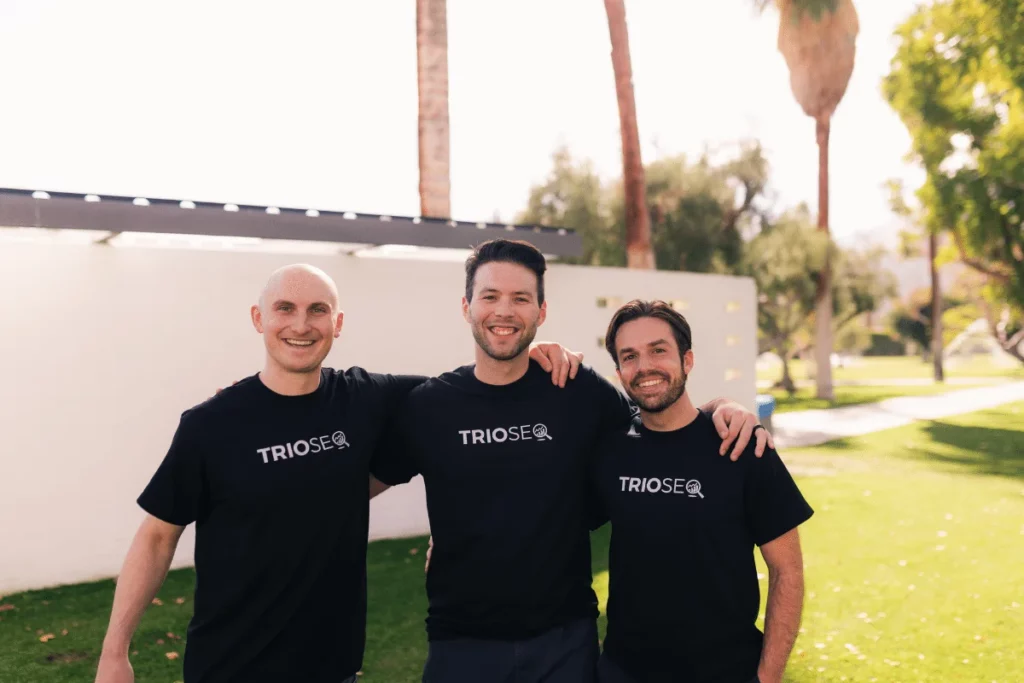 Nathan stands left, Steven in center, Connor right, all in TRIOS® t-shirts outdoors.